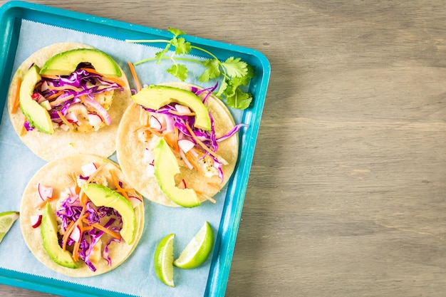 Tacos de pescado fresco con bacalao y col morada sobre una tortilla de maíz blanco.