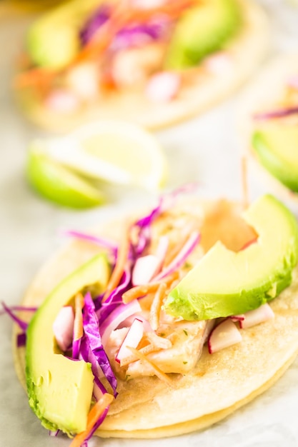 Tacos de pescado fresco con bacalao y col morada sobre una tortilla de maíz blanco.