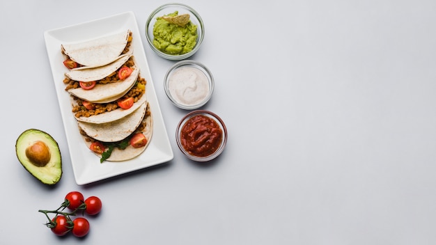 Foto tacos en el plato junto a las verduras y salsas