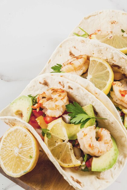 Tacos de tortilla con ensalada tradicional casera, perejil, limón fresco, aguacate y camarones a la parrilla