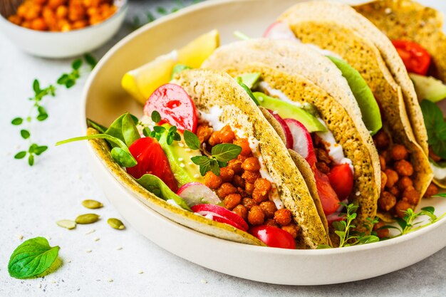 Tacos vegan com grão cozido, abacate, molho e legumes.