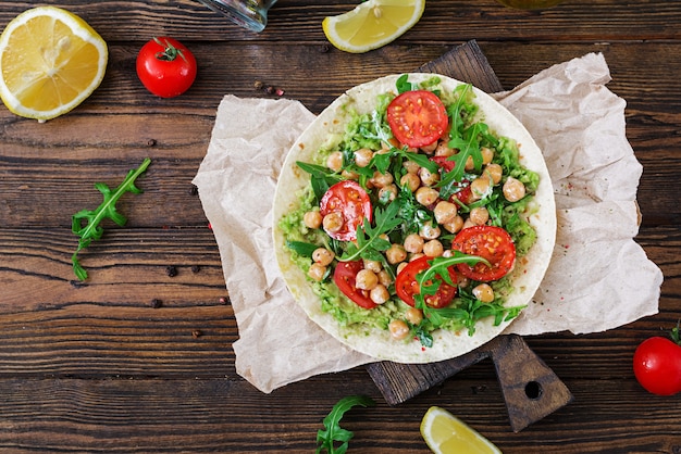 Tacos veganos con guacamole, garbanzos, tomates y rúcula. Comida sana. Desayuno útil Endecha plana. Vista superior