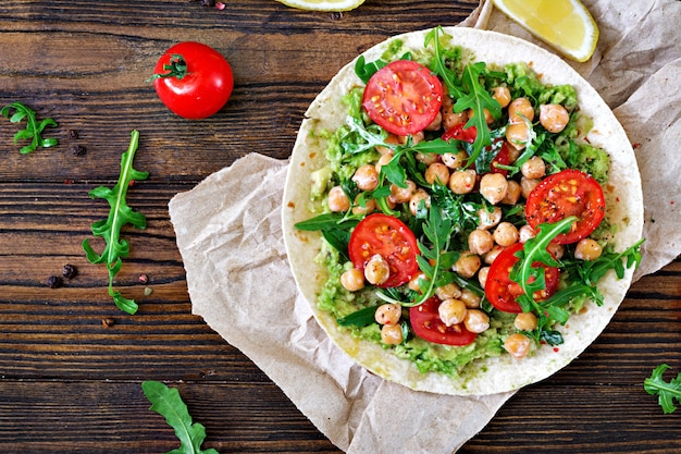 Tacos veganos con guacamole, garbanzos, tomates y rúcula. Comida sana. Desayuno útil Endecha plana. Vista superior