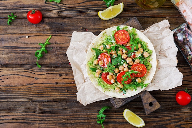 Tacos veganos con guacamole, garbanzos, tomates y rúcula. Comida sana. Desayuno útil Endecha plana. Vista superior