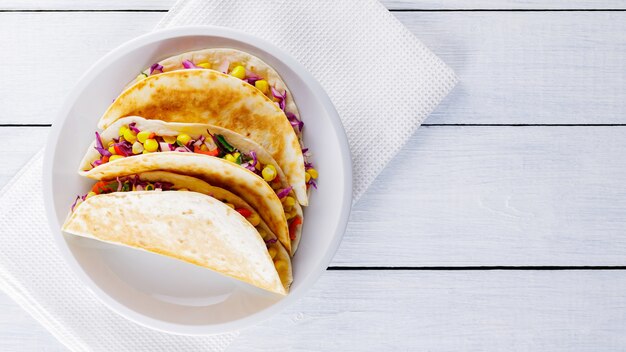 Tacos veganos con maíz, repollo morado y tomates en un plato blanco. Tacos mexicanos con diferentes verduras en pizarras blancas. Comida sana. cocina mexicana