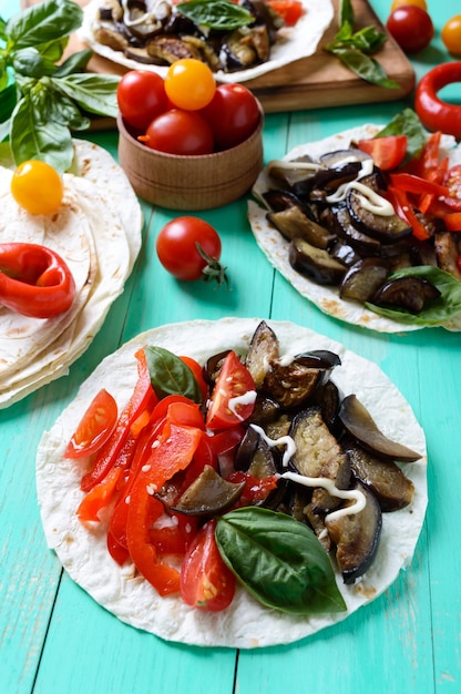 Tacos vegetarianos con berenjena, tomates cherry, pimientos en mesa de madera brillante