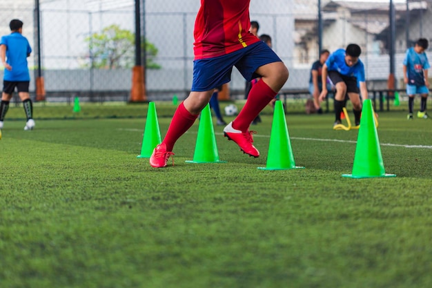 Tácticas de pelota de fútbol en campo de hierba con barrera para entrenar a los niños saltando