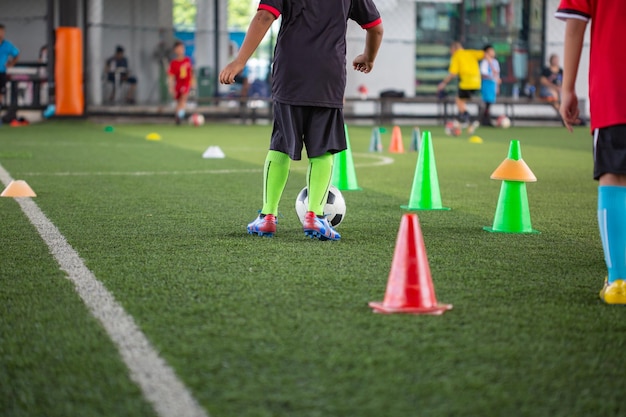 Foto tácticas de pelota de fútbol en el campo de hierba con cono para el entrenamiento tailandés en el fondo entrenamiento de niños en la academia de fútbol