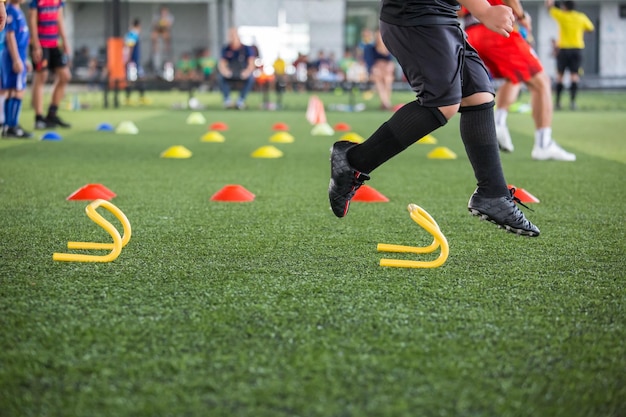 Tácticas de pelota de fútbol en el campo de hierba con cono para entrenar a los niños en la academia de fútbol