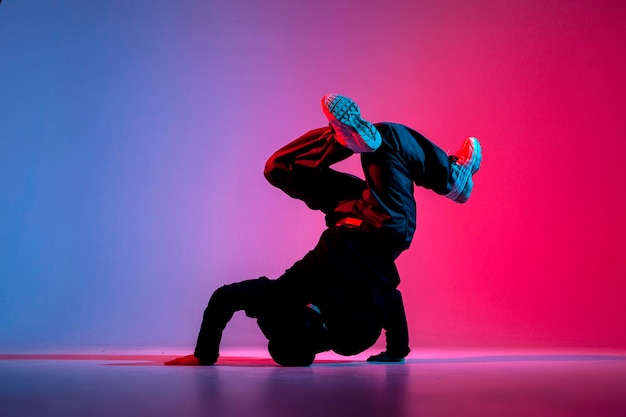 Tänzerin macht akrobatische Tricks und tanzt Breakdance in neonroter und blauer Beleuchtung