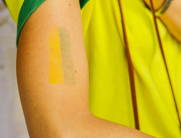 Tätowiere einen Arm mit Gelb und Grün, den Farben der brasilianischen Flagge