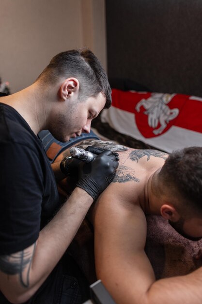 Tätowierer macht zu Hause ein Tattoo auf dem Rücken eines Mannes