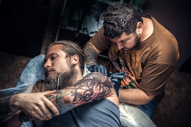 Tätowierer zeigt den Prozess der Tätowierung im Tattoo-Studio./Meister beim Tätowieren im Tattoo-Studio.