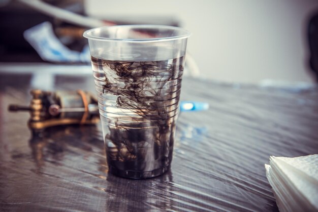 Tätowierfarbe verteilt sich im Wasserglas.