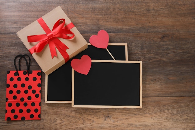 Tafel mit Einkaufstasche, Geschenk und Herzen auf Holztisch.