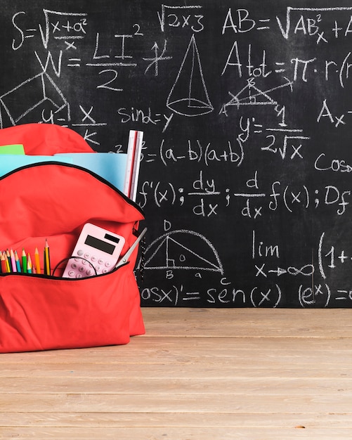 Tafel mit mathematischen Formeln und roter Schultasche für Mädchen