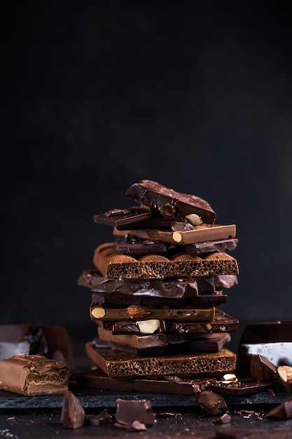 Foto tafel mit schokoladenturmstücken haselnuss- und mandeldunkle brocken gebrochener schokolade fotokonzept für süße speisen