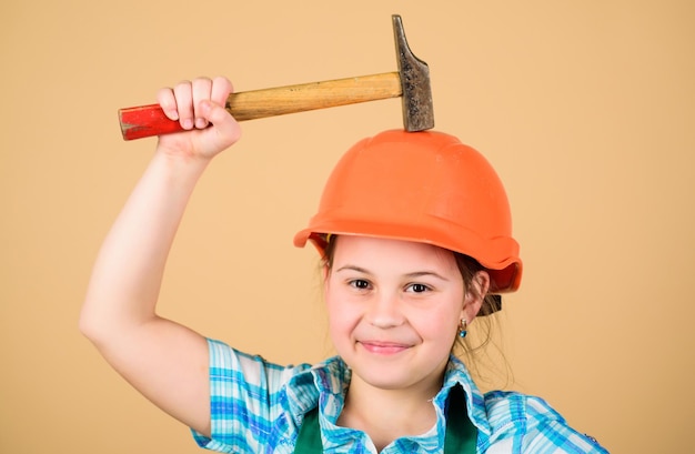 Foto tag der arbeit. 1. mai. sicherheitsexperte. zukünftiger beruf. vorarbeiterinspektor. reparatur. kleines mädchen im helm mit hammer. kinderarbeiter im schutzhelm. kleines mädchen, das in der werkstatt repariert. selbstbewusster mechaniker.