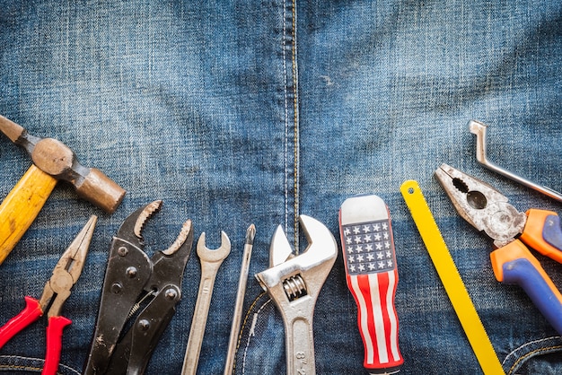 Tag der Arbeit, 1. Mai. Viele handliche Werkzeuge mit Leerzeichen auf Jeans Hintergrundtextur.