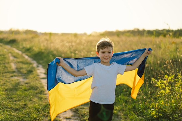 Tag der Unabhängigkeit der Ukraine Ukrainischer Kindjunge im weißen T-Shirt mit gelber und blauer Flagge der Ukraine im Feld Flagge der Ukraine Tag der Verfassung Stehen Sie mit der Ukraine Save Ukraine