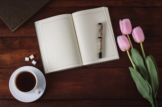 Tagebuch, Tasse Kaffee, Tulpen, Buch auf dem dunklen Holztisch