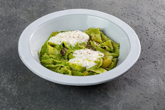 Tagilatelle Pasta Spinach Green in weißer Platte auf konkretem Hintergrundkopierraum