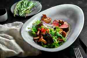 Foto tagliata de carne de res con verduras de primer plano de fondo gris bajo