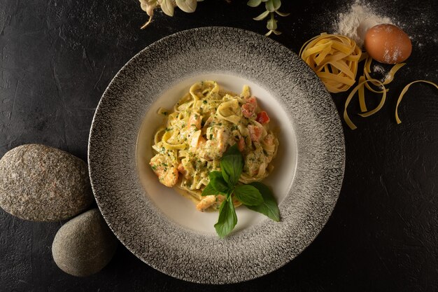 Tagliatelle con camarones y albahaca. Plato caliente de pasta y mariscos sobre un fondo oscuro