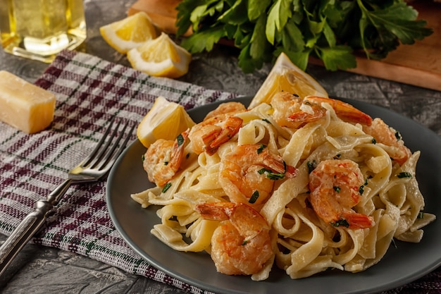 Tagliatelle com camarão e salsa em mesa cinza