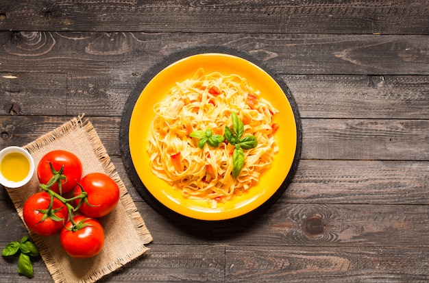 Tagliatelle com tomate e manjericão, feitos em casa, em uma mesa de madeira,