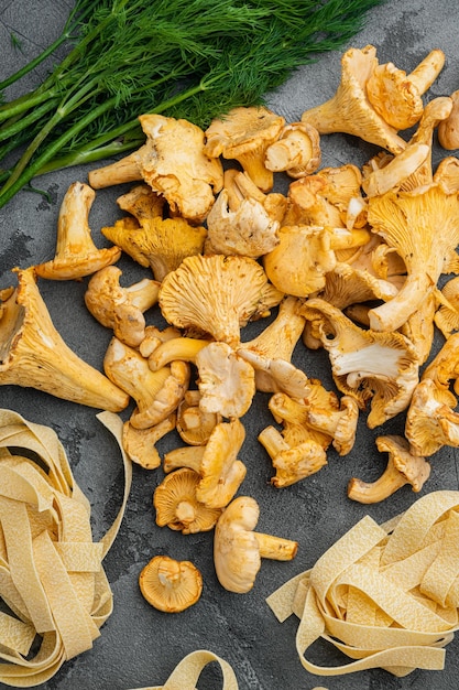 Tagliatelle cru com ingredientes de cogumelos chanterelle colocados no fundo da mesa de pedra cinzenta vista superior plana