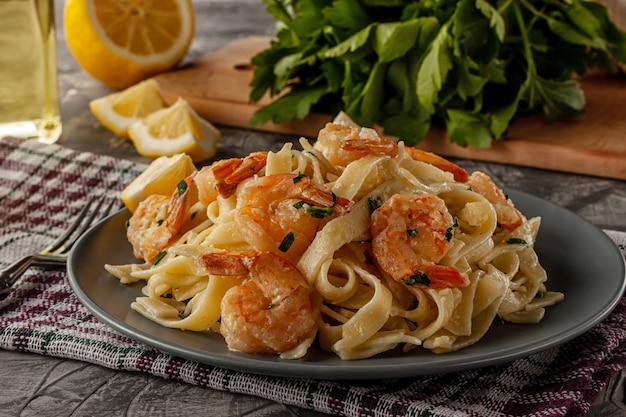 Tagliatelle con gambas y perejil sobre una mesa gris