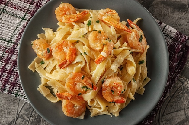 Tagliatelle con gambas y perejil sobre una mesa gris