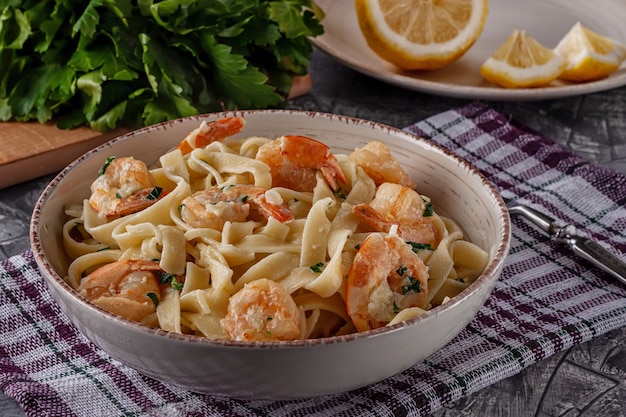 Tagliatelle mit Garnelen und Petersilie auf einem grauen Tisch