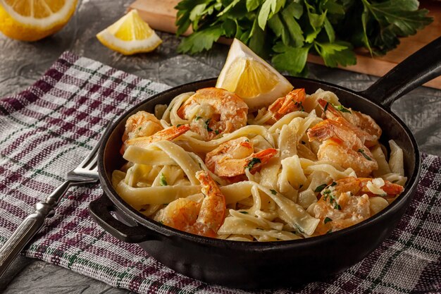 Tagliatelle mit Garnelen und Petersilie auf einem grauen Tisch