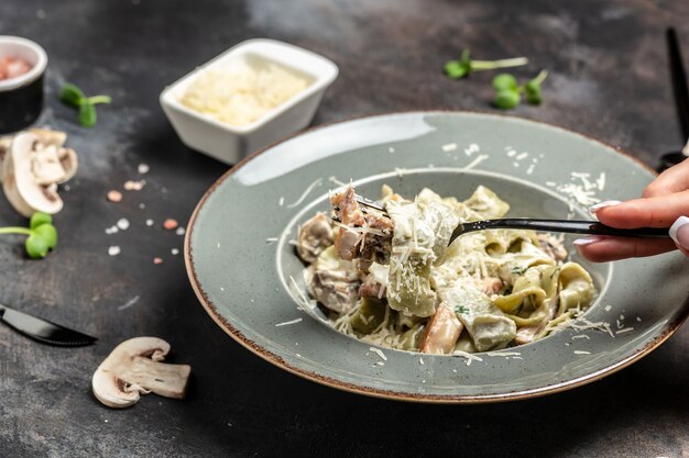 Tagliatelle-Nudeln mit Champignons und Hühnchen in cremiger Käsesauce. Restaurantmenü, Diät, Kochbuchrezept.