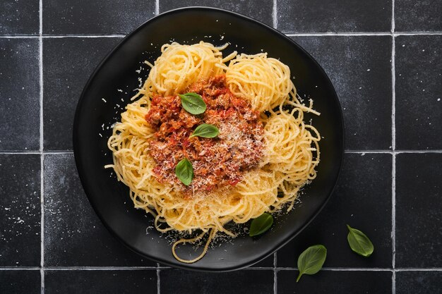 Tagliatelle-Nudeln mit Fleischbällchen in Tomatensauce, Basilikum und Parmesankäse auf schwarzem Stein- oder Betonhintergrund Traditionelles italienisches Gericht und Küche Draufsicht mit Kopierbereich