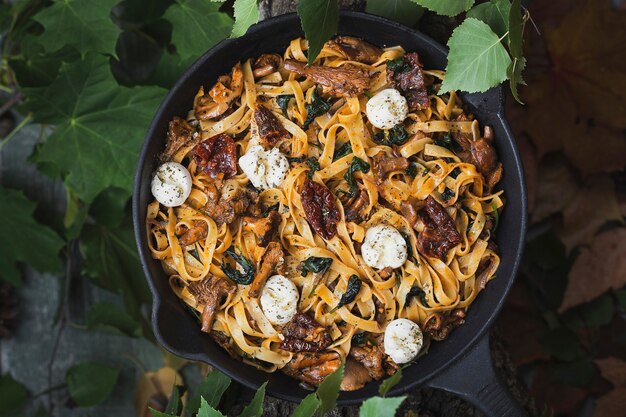 Tagliatelle-Nudeln mit Pfifferlingen, Spinat, sonnengetrockneten Tomaten und Mozzarella