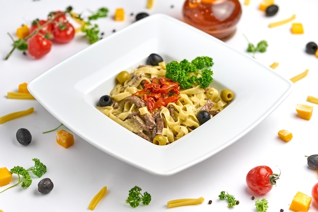 Foto tagliatelle-nudeln mit rindersteakstreifen und sonnengetrockneten tomaten mit geriebenem parmesan