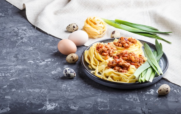 Tagliatelle pasta boloñesa con carne picada sobre un fondo de hormigón negro