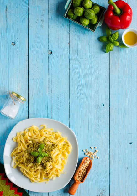 Tagliatelle de pasta con salsa de pesto y otras verduras sobre un fondo de madera. Vista superior