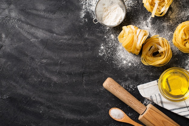 Tagliatelle Pasta ungekocht, macht Spaghetti Hintergrund, schwarze Textur, Draufsicht, Kopierraum