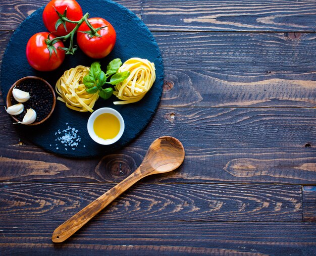 Tagliatelle con tomate y albahaca, hecho en casa sobre una mesa de madera