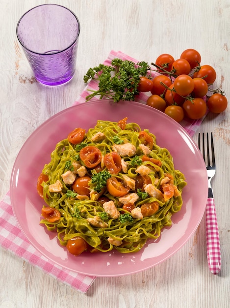 Foto tagliatelle verde con salmón fresco y tomates