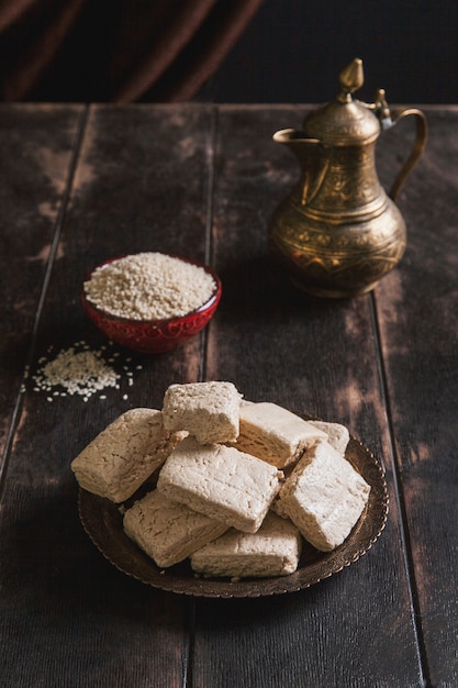 Tahini-Halva-Stücke, Sesamsamen in einer Schüssel, ein Vintage-Krug