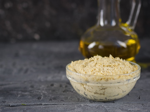 Tahini de pasta fresca de semillas de sésamo con aceite de oliva y ajo en una mesa de madera negra.