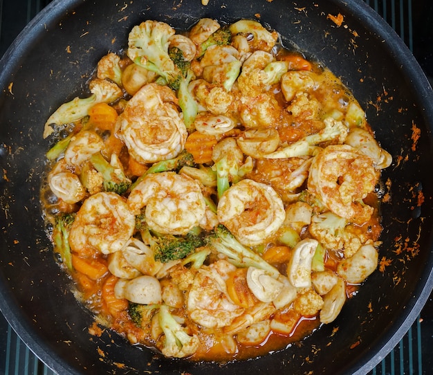 Foto tailandês picante mexa legumes fritos e camarões com pasta de curry vermelho picante em uma panela