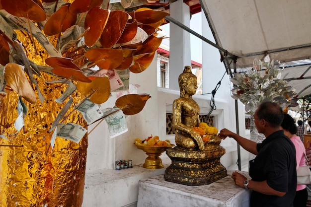 Tailandia, Bangkok, distrito de Yai, templo de Arun (Wat Arun Ratchawararam), pareja tailandesa ofreciendo flores a una estatua de Buda