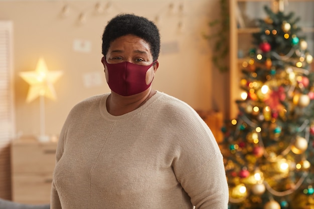 Taille hoch Porträt der älteren afroamerikanischen Frau, die Maske trägt und Kamera betrachtet, während Weihnachten feiert, Raum kopieren