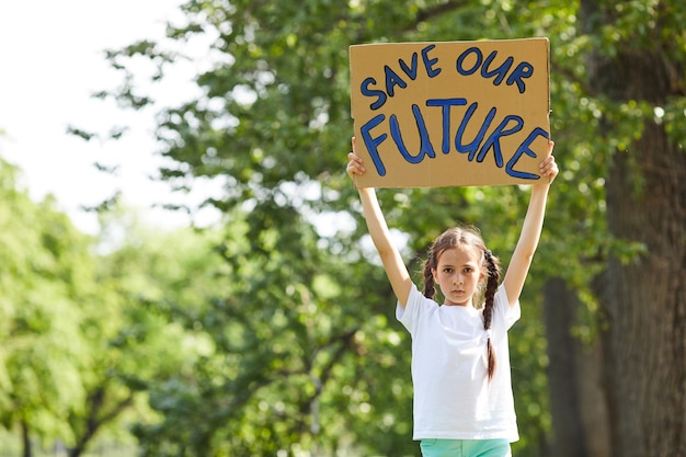 Taille hoch Porträt des niedlichen Mädchens, das Zeichen mit SAVE FUTURE hält, während für Natur im Freien protestieren, Raum kopieren